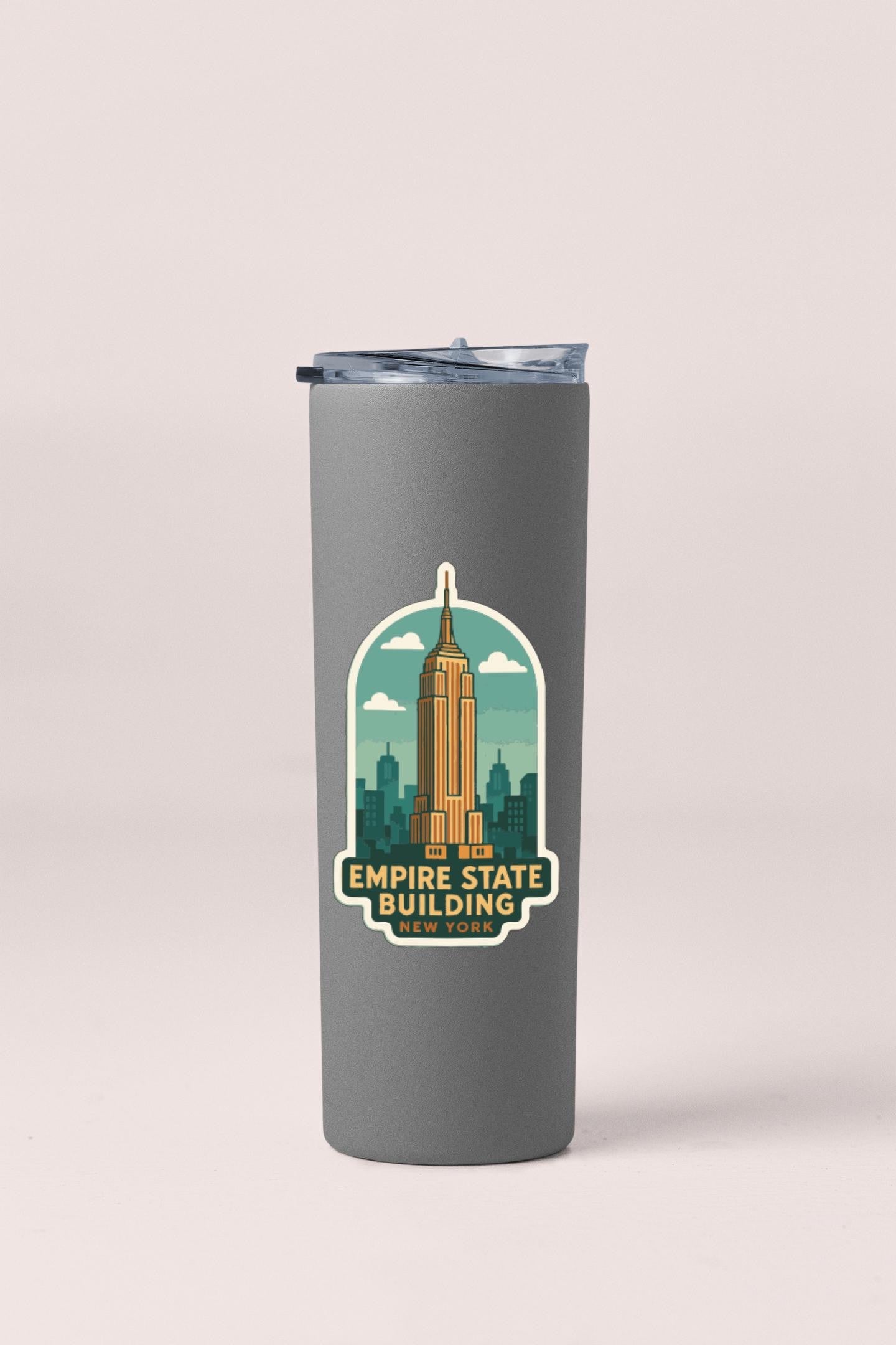 A gray insulated tumbler with a sticker depicting the Empire State Building and the text "Empire State Building NEW YORK".