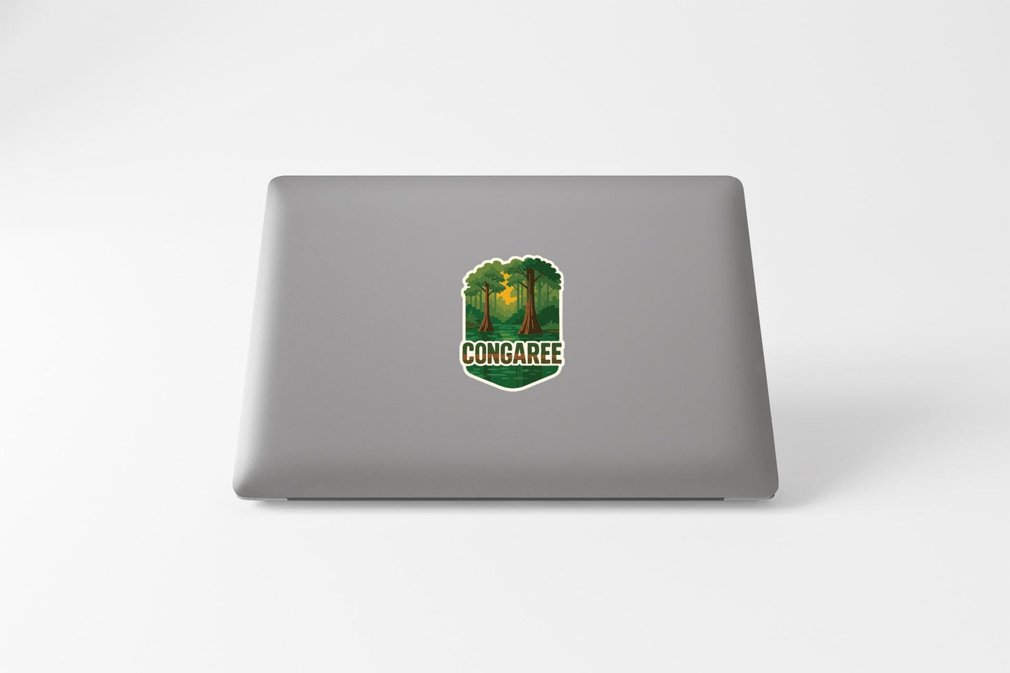 a sticker with a forest scene and the word "CONGAREE" printed on a grey laptop.
