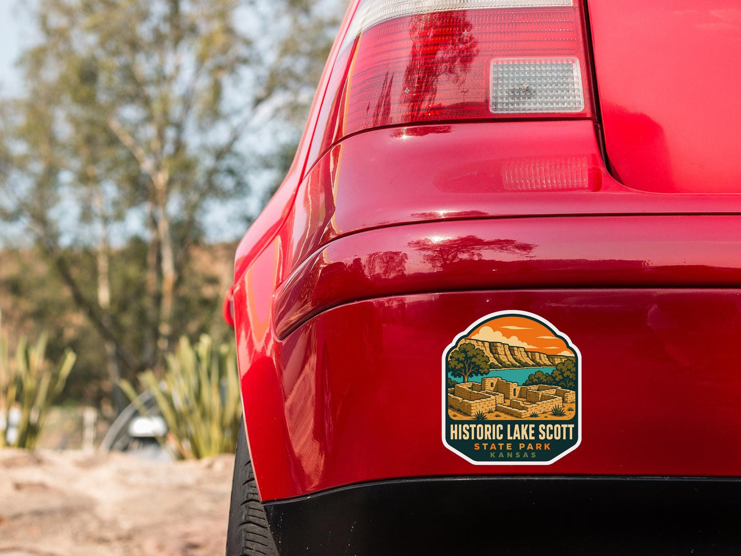 the rear end of a red car with a sticker on the back window that says "Historic Lake Scott State Park Kansas".