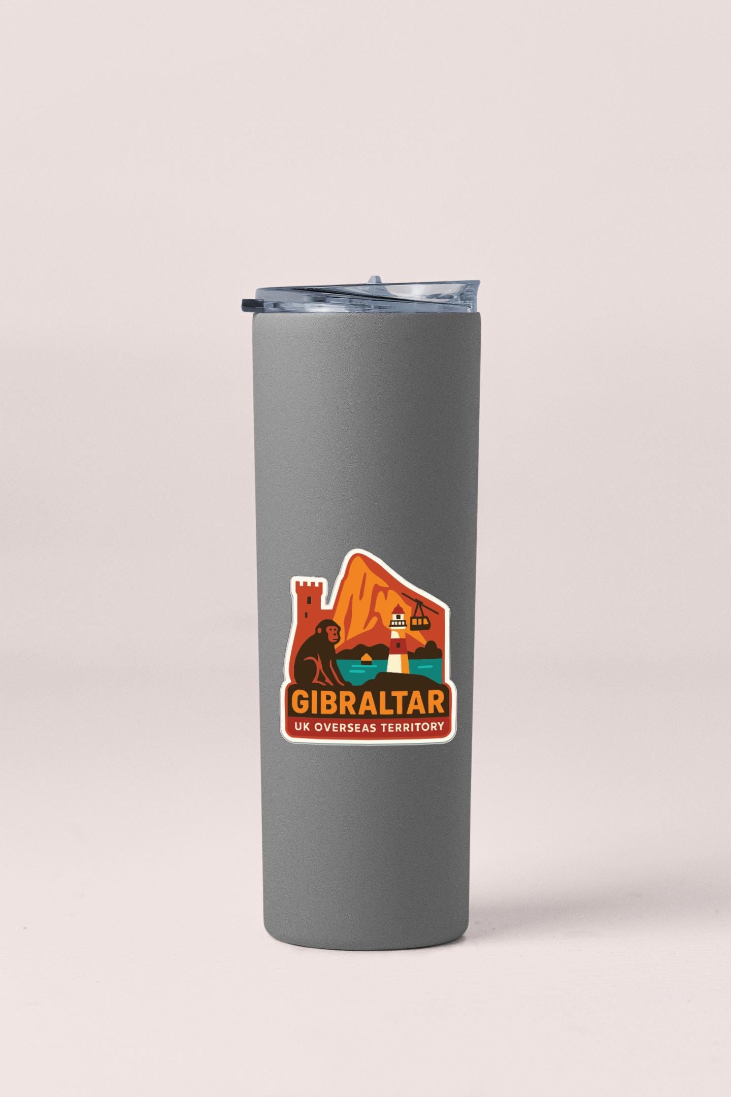 A gray insulated tumbler with a sticker on it, featuring an illustration of a mountain and a castle.