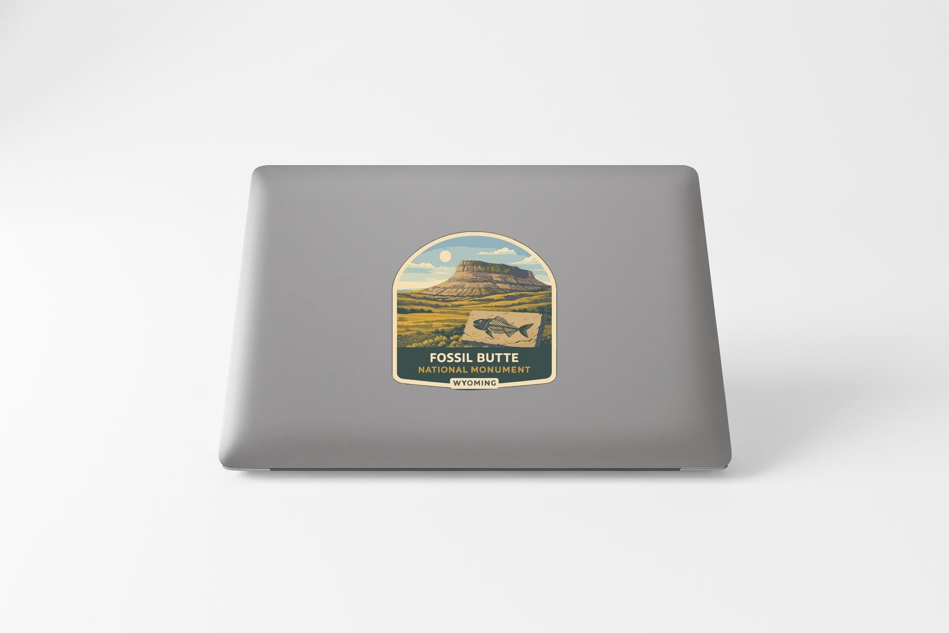 a sticker on a laptop with a mountain landscape and a fish.