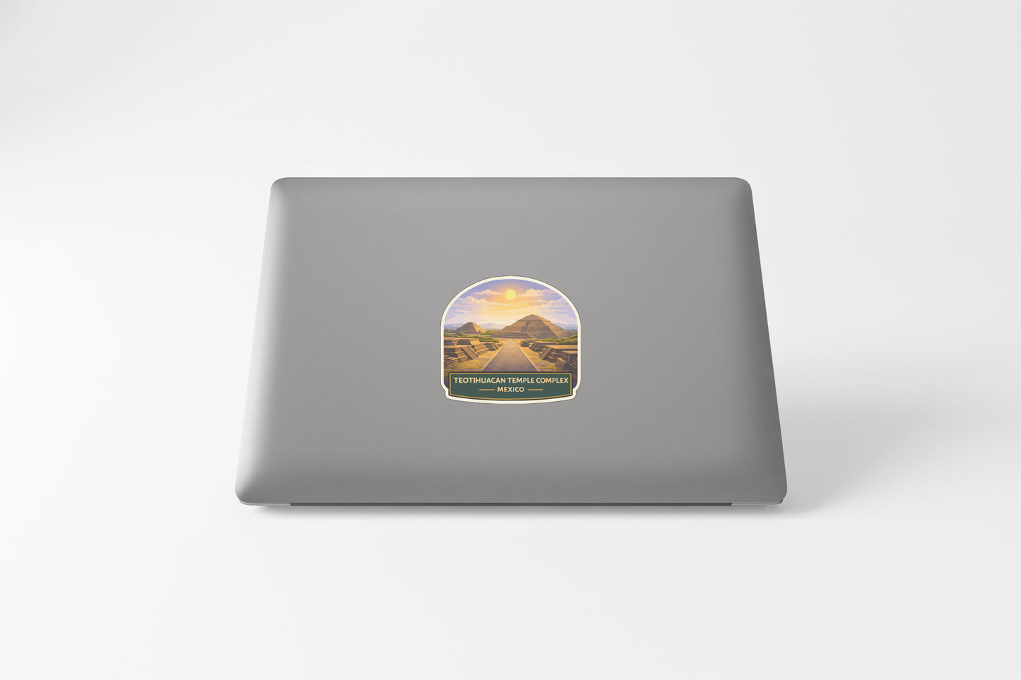 A sticker on the back of a laptop computer, depicting a scenic landscape with mountains and a winding road.
