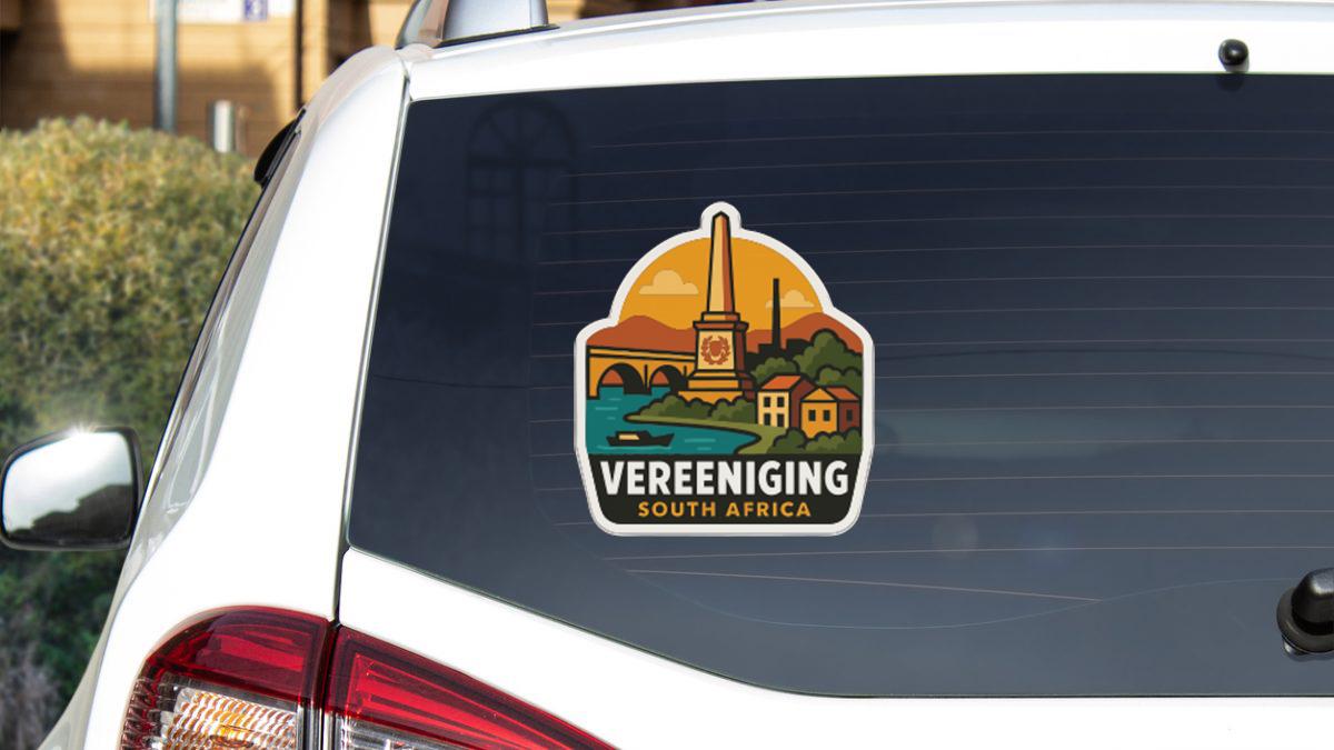 a sticker on the rear window of a car, depicting a scenic view of a town or city with a monument or landmark.