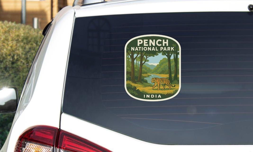 A sticker on the rear window of a car, depicting a tiger in a forest setting, with the text "PENCH NATIONAL PARK INDIA".