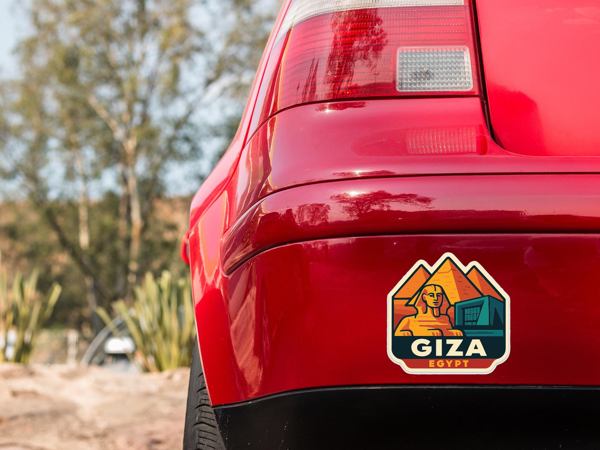 the rear end of a red car with a sticker on the trunk that says "Giza Egypt".