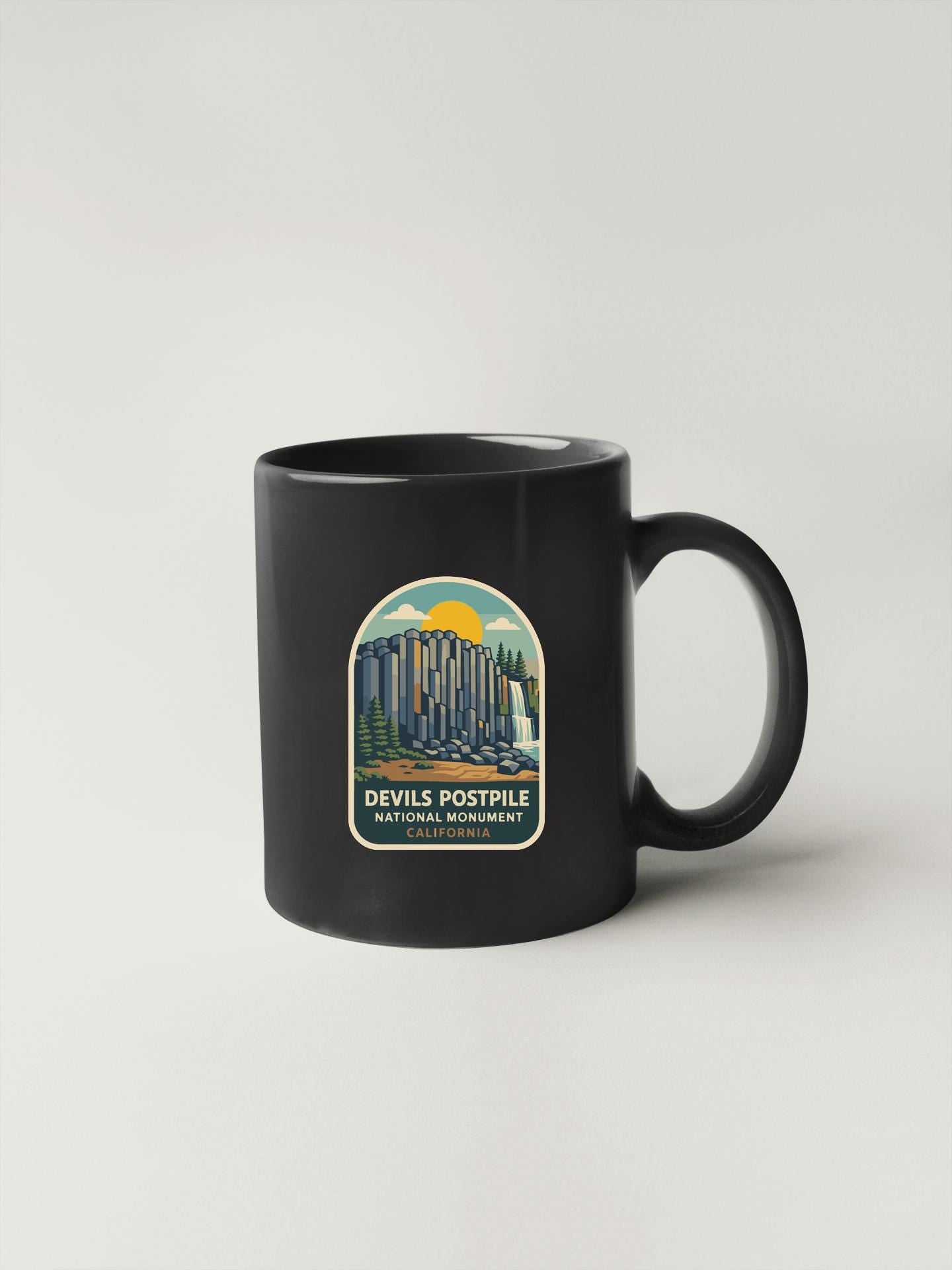 A black coffee mug with a label that says "DEVILS POSTPILE NATIONAL MONUMENT CALIFORNIA".