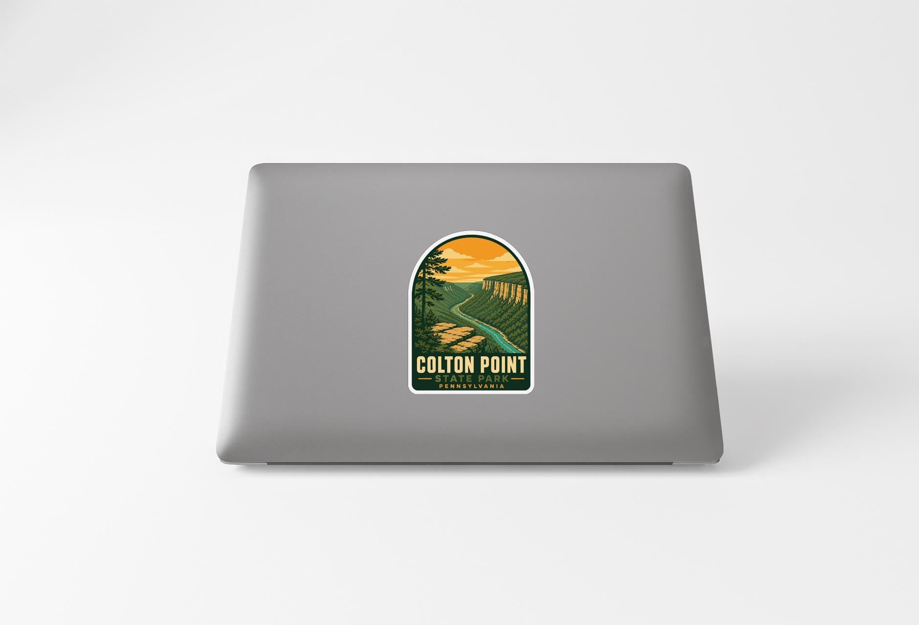 A sticker on the back of a laptop, depicting a scenic landscape with a winding road and a sunset in the background.