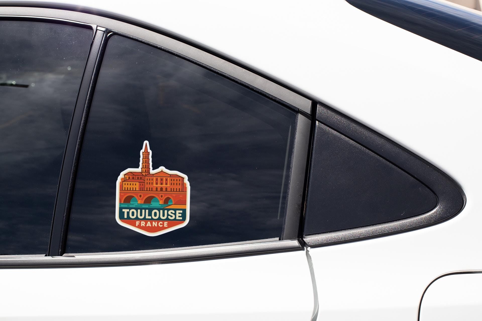 A sticker on the side of a car window, featuring a building and the text "TOULOUSE FRANCE".