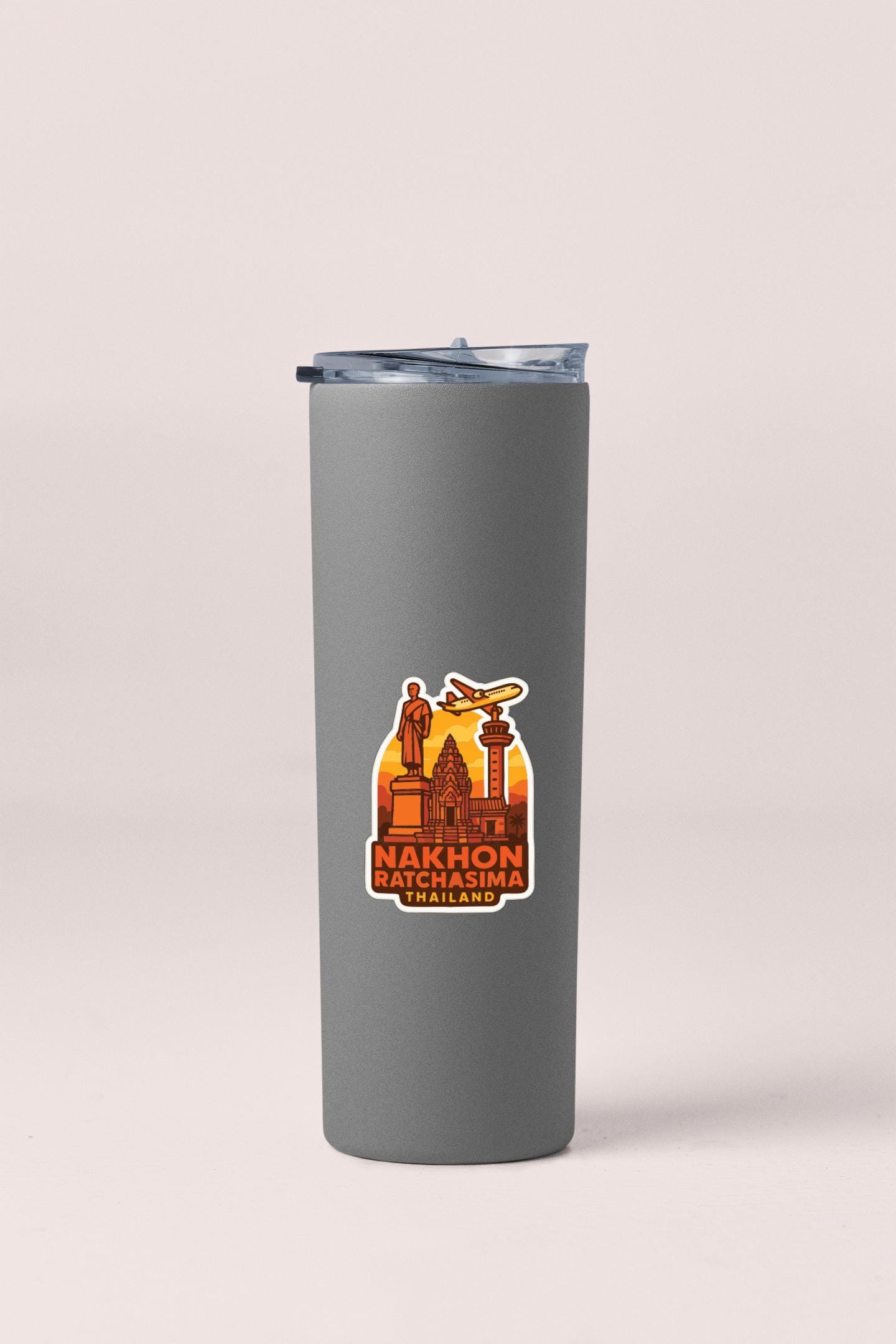 A gray insulated tumbler with a sticker depicting a city skyline and a statue.
