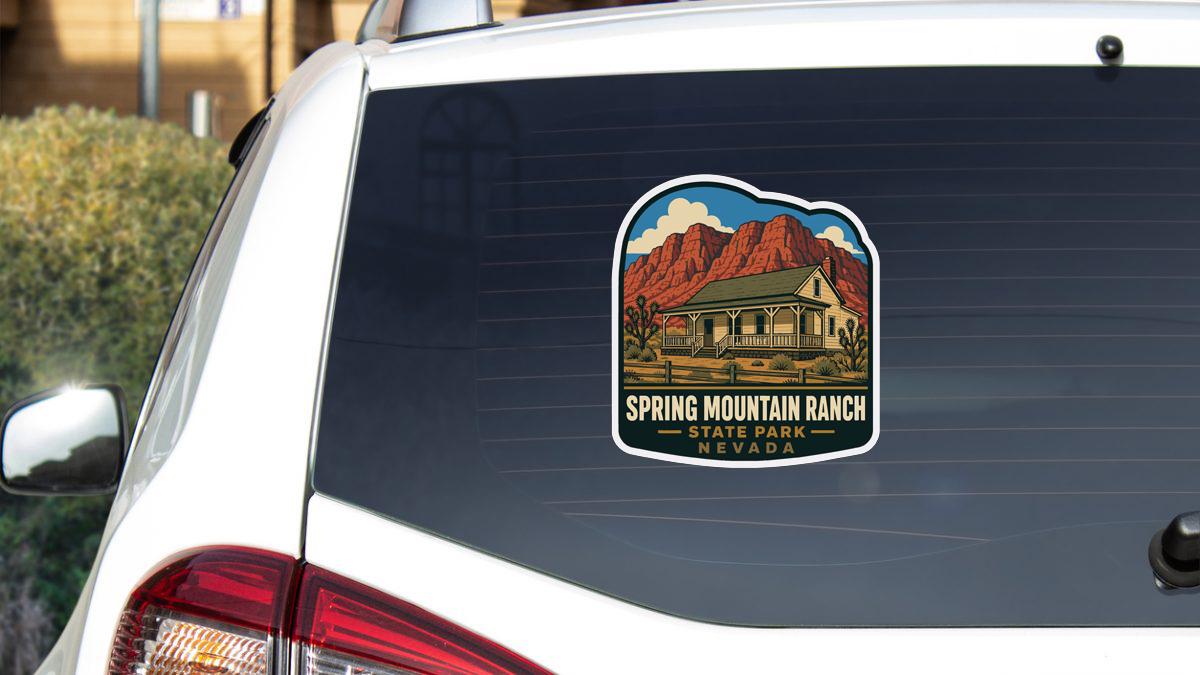 A sticker on the rear window of a vehicle, depicting a house and mountains, with the text "Spring Mountain Ranch State Park Nevada" printed on it.