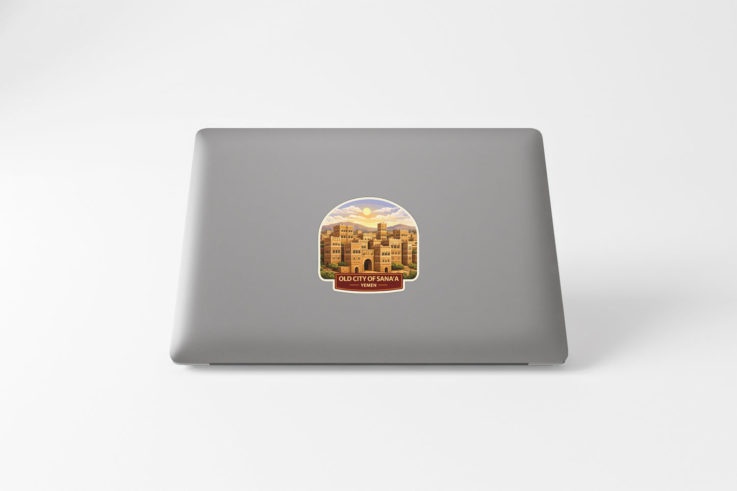 a sticker on the back of a laptop, depicting a cityscape with buildings and a sunset in the background.