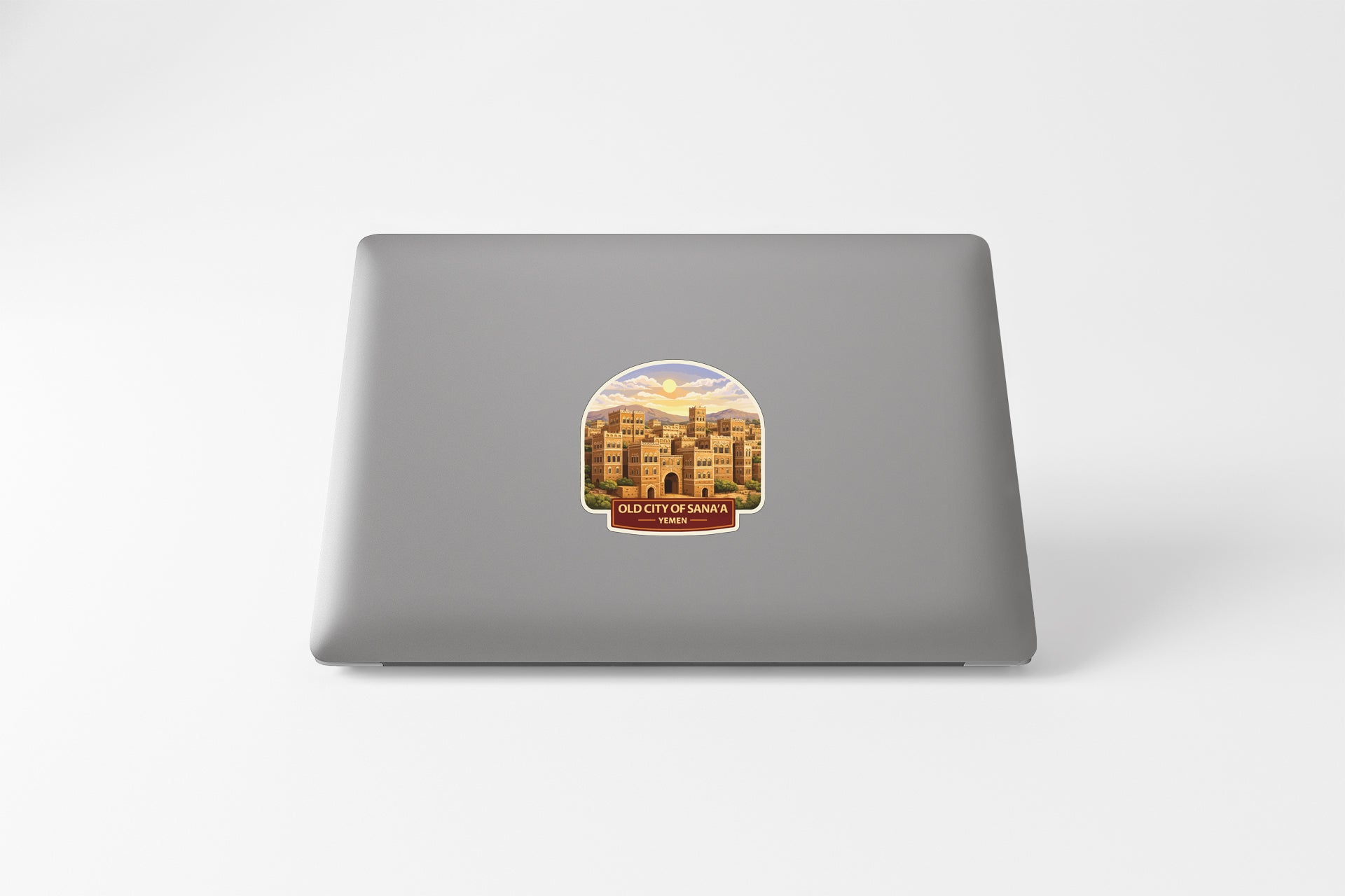 a sticker on the back of a laptop, depicting a cityscape with buildings and a sunset in the background.