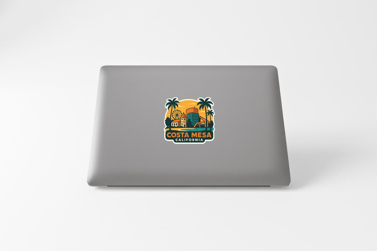 a sticker with a tropical beach scene and the text "COSTA MESA CALIFORNIA" printed on a laptop.