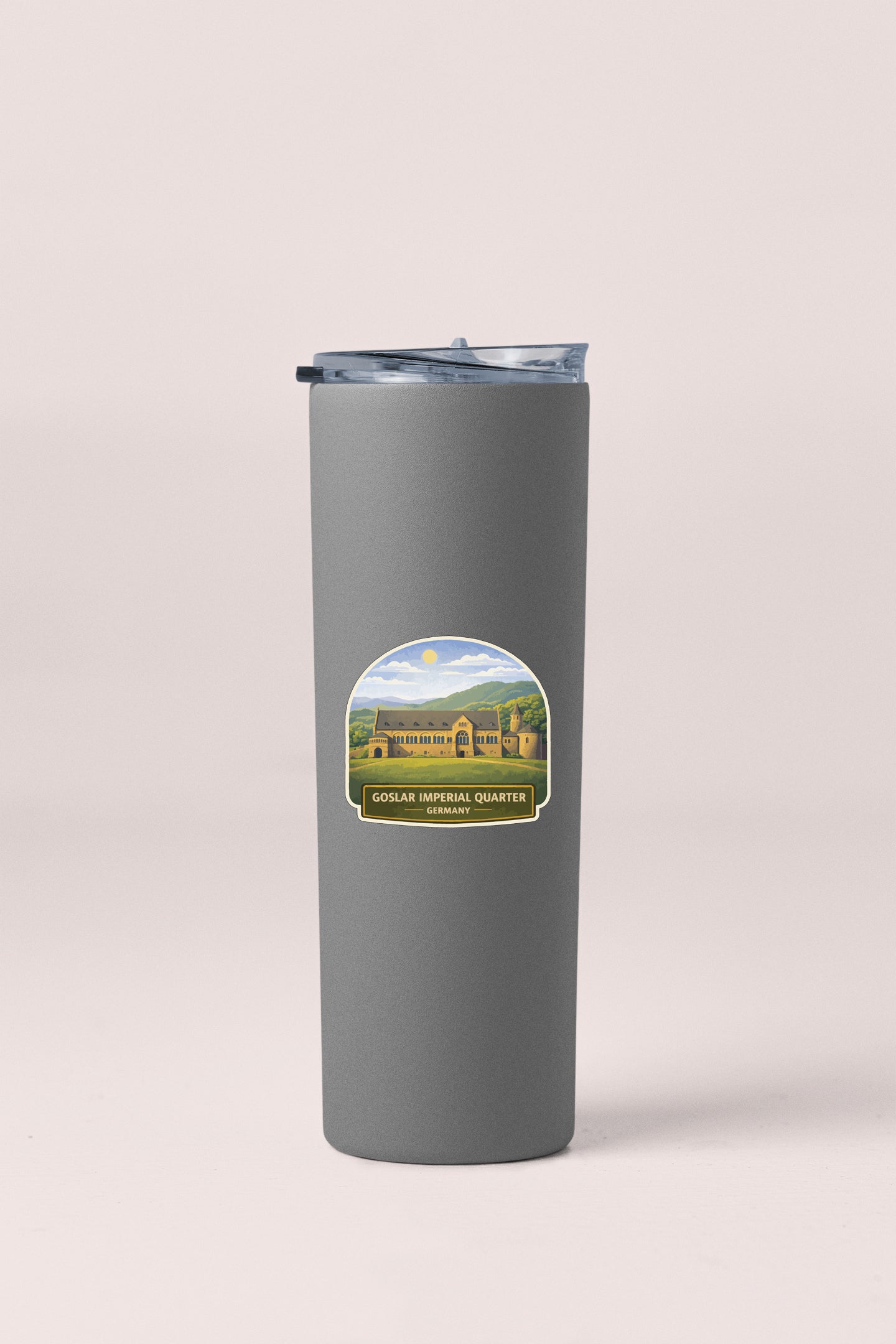 A gray insulated tumbler with a label that features a scenic image of a building and a mountain landscape.