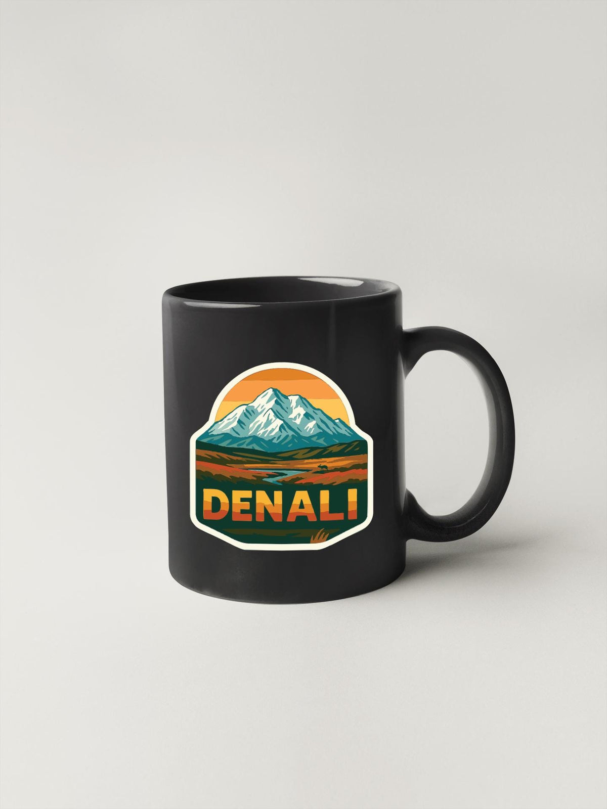 A black coffee mug with a mountain landscape sticker on it.