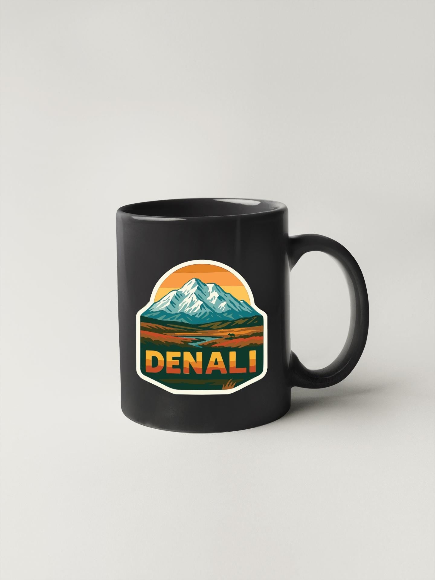 A black coffee mug with a mountain landscape sticker on it.