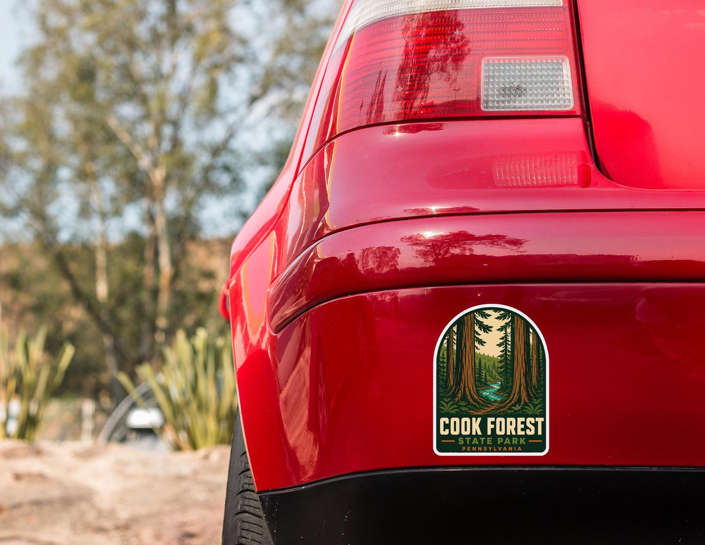 the rear end of a red car with a sticker on the trunk that says "Cook Forest" and "Pennsylvania".