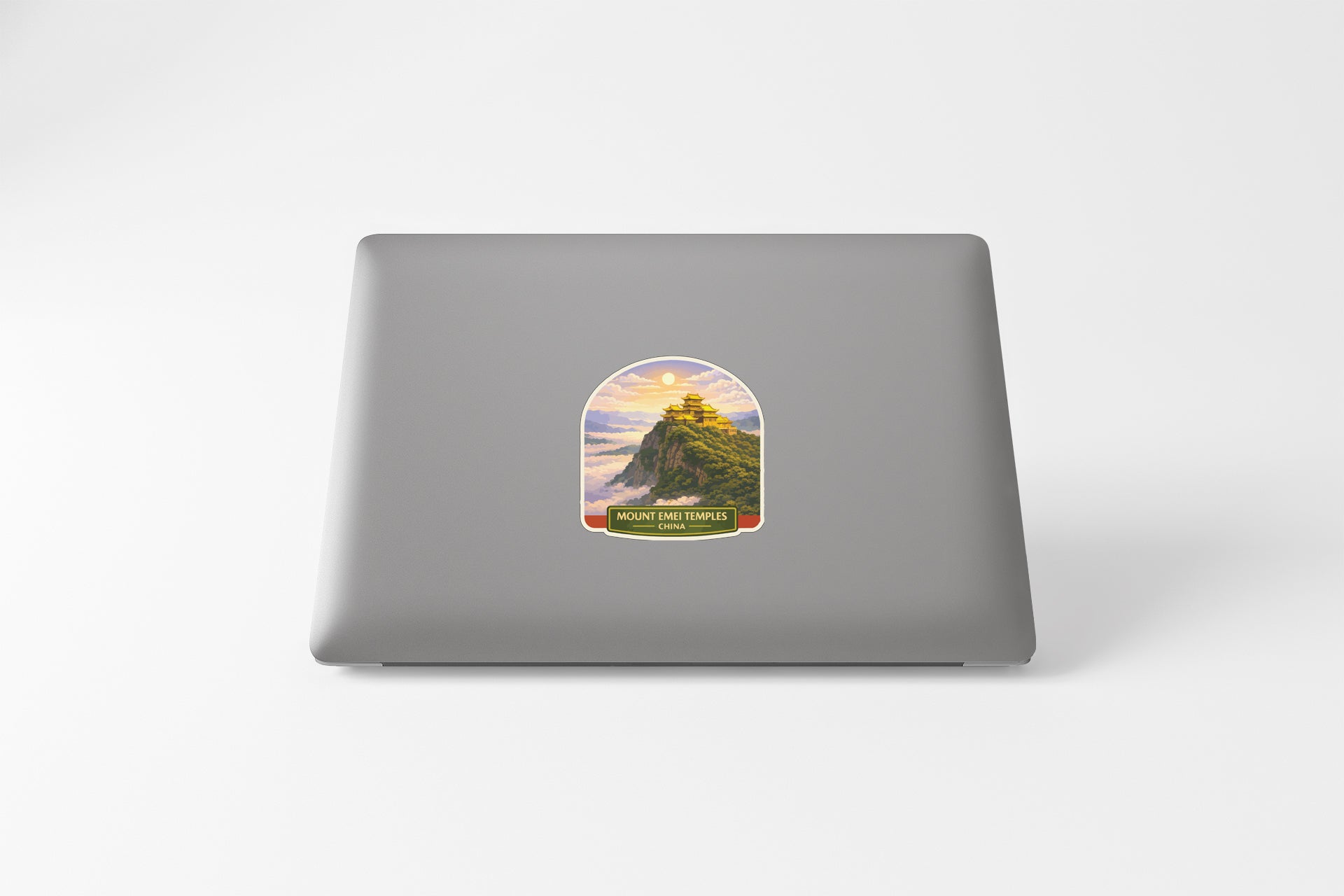 a sticker on the back of a laptop, depicting a mountain landscape with a temple in the distance.