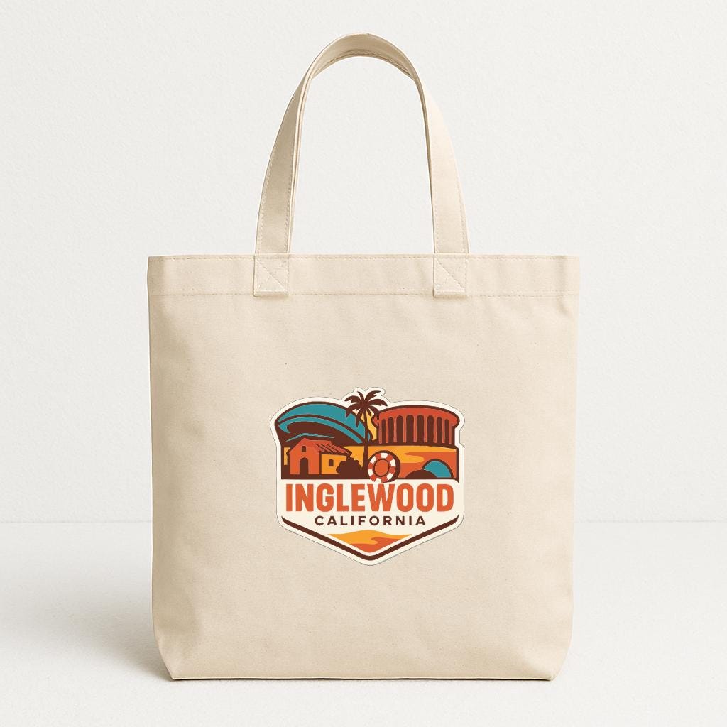 A beige tote bag with a colorful graphic of a city and the text "INGLEWOOD CALIFORNIA" printed on it.