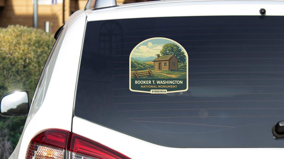 a sticker on the rear window of a white car, depicting a cabin in a rural setting.