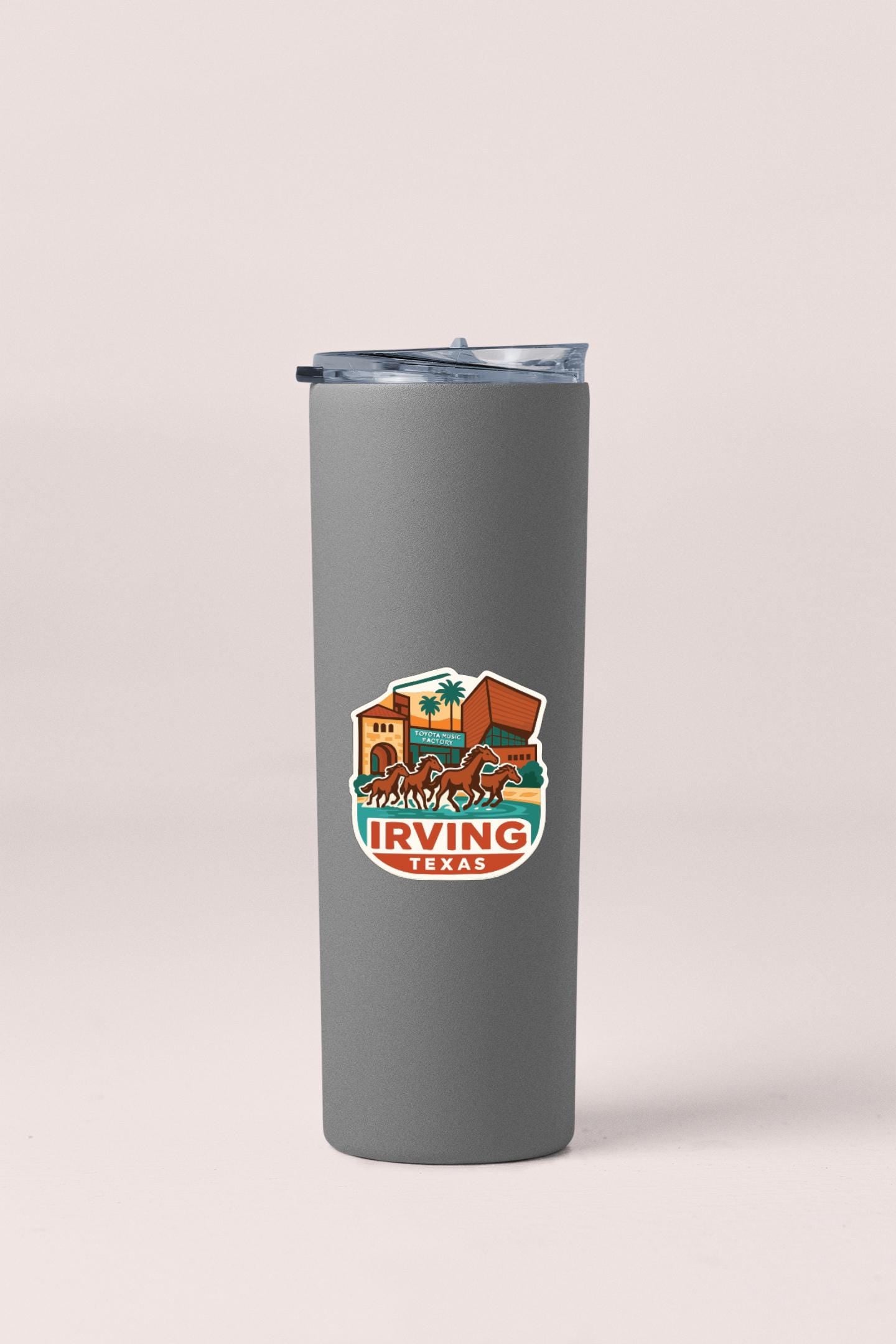 A gray insulated tumbler with a lid and a colorful logo that says " Irving, TX".