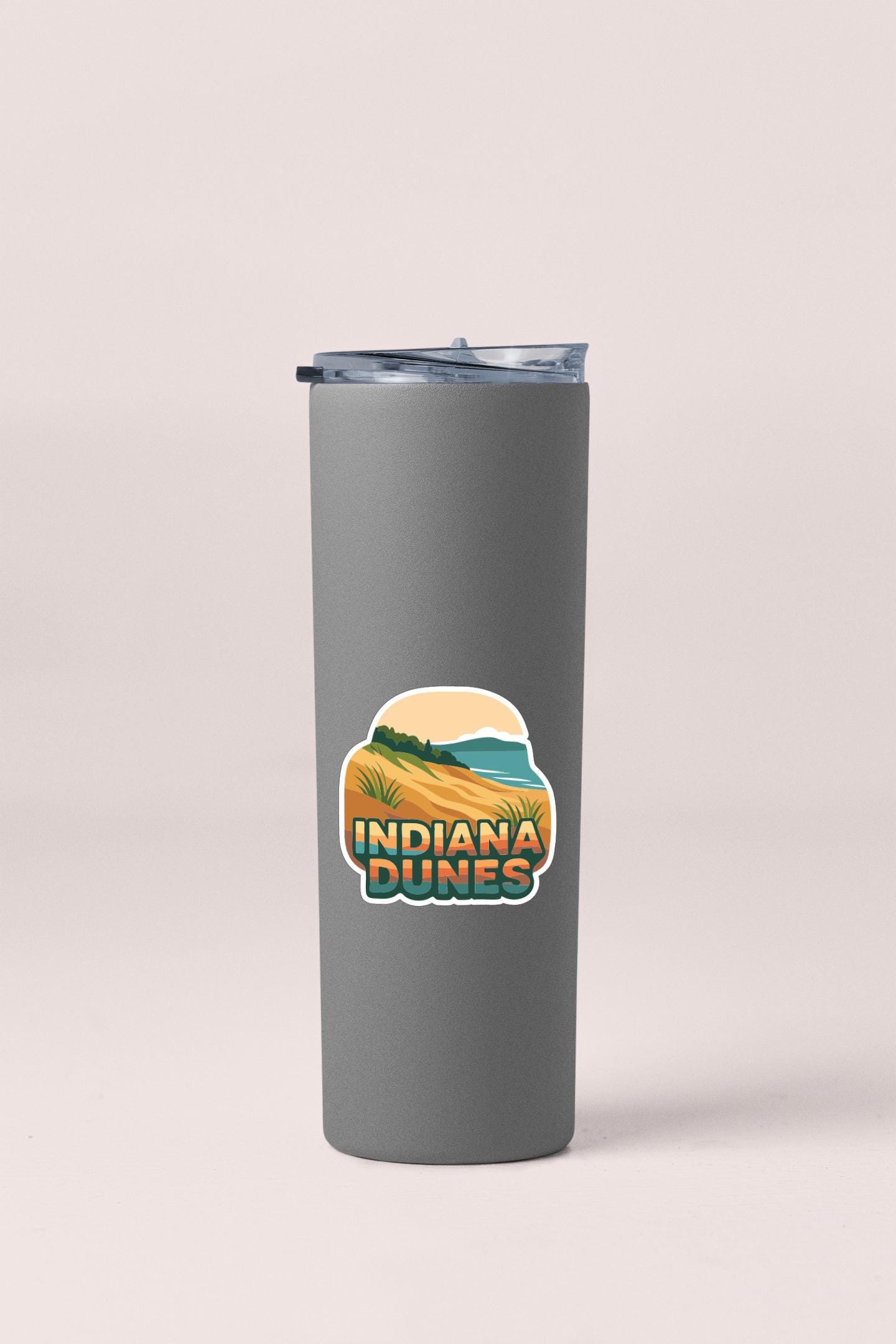 A gray insulated tumbler with a lid and a sticker that says "Indiana Dunes".