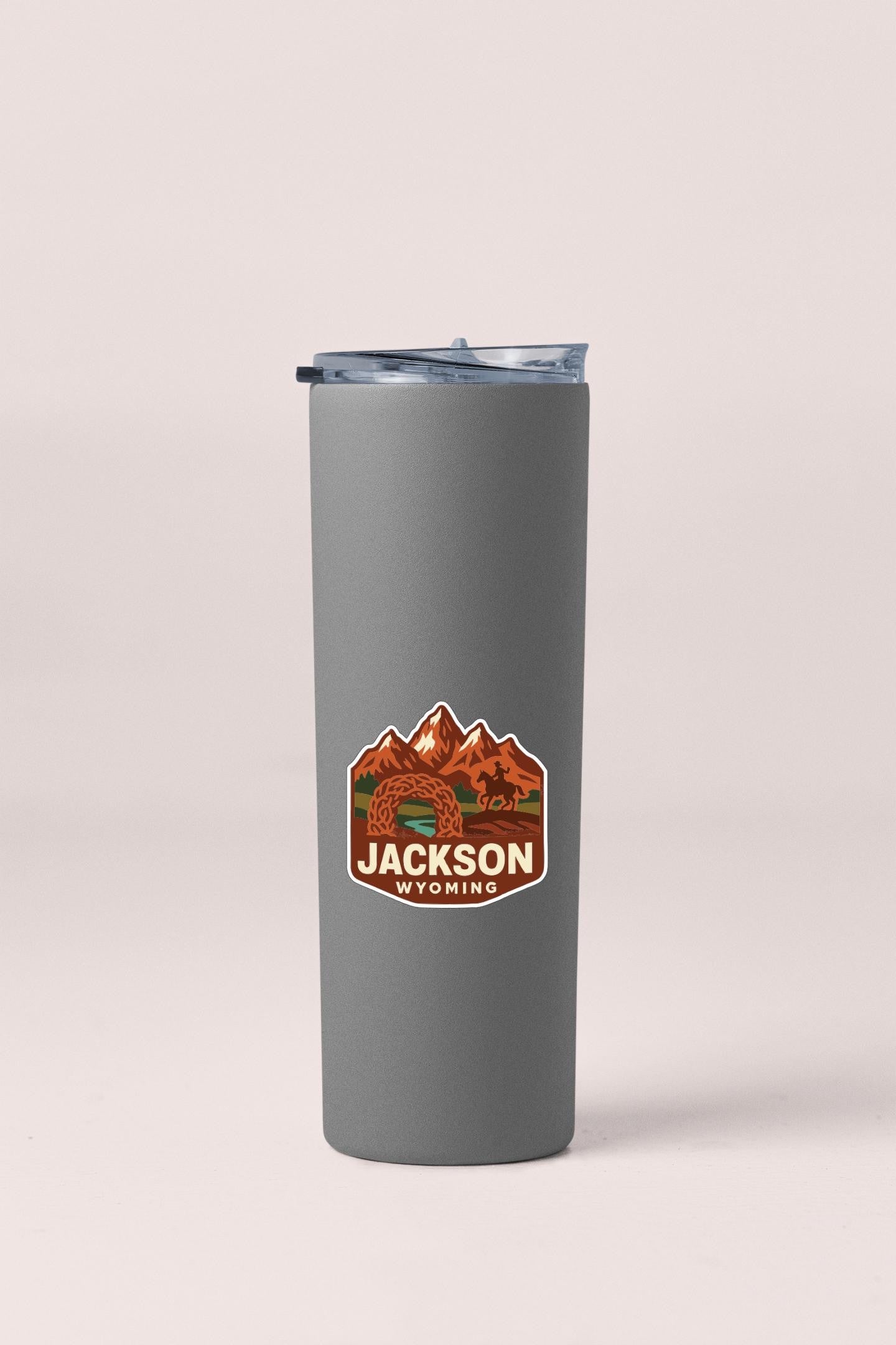 A gray insulated tumbler with a mountain and river design sticker on it.