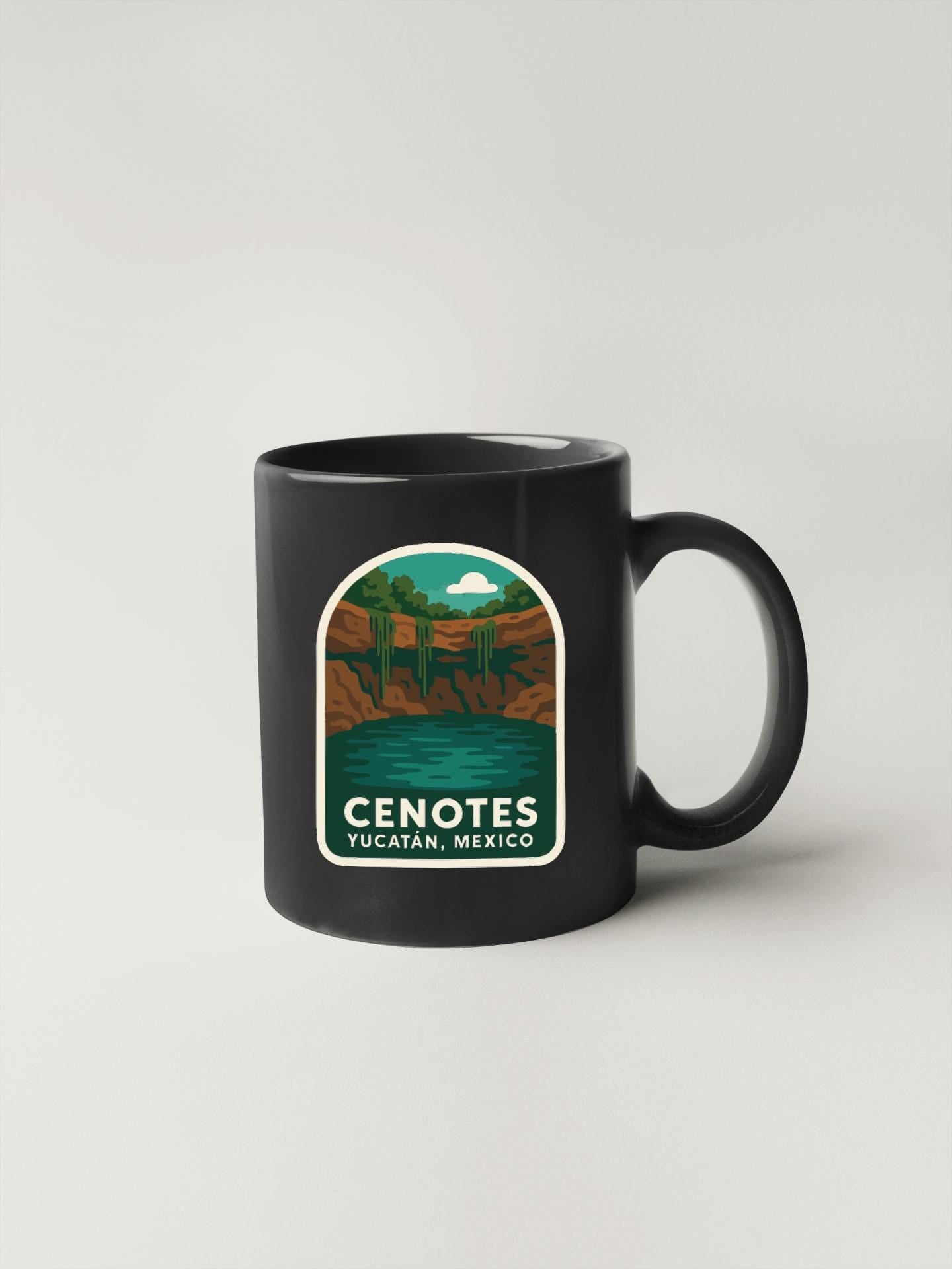A black coffee mug with a graphic design depicting a scenic landscape with a lake and mountains.
