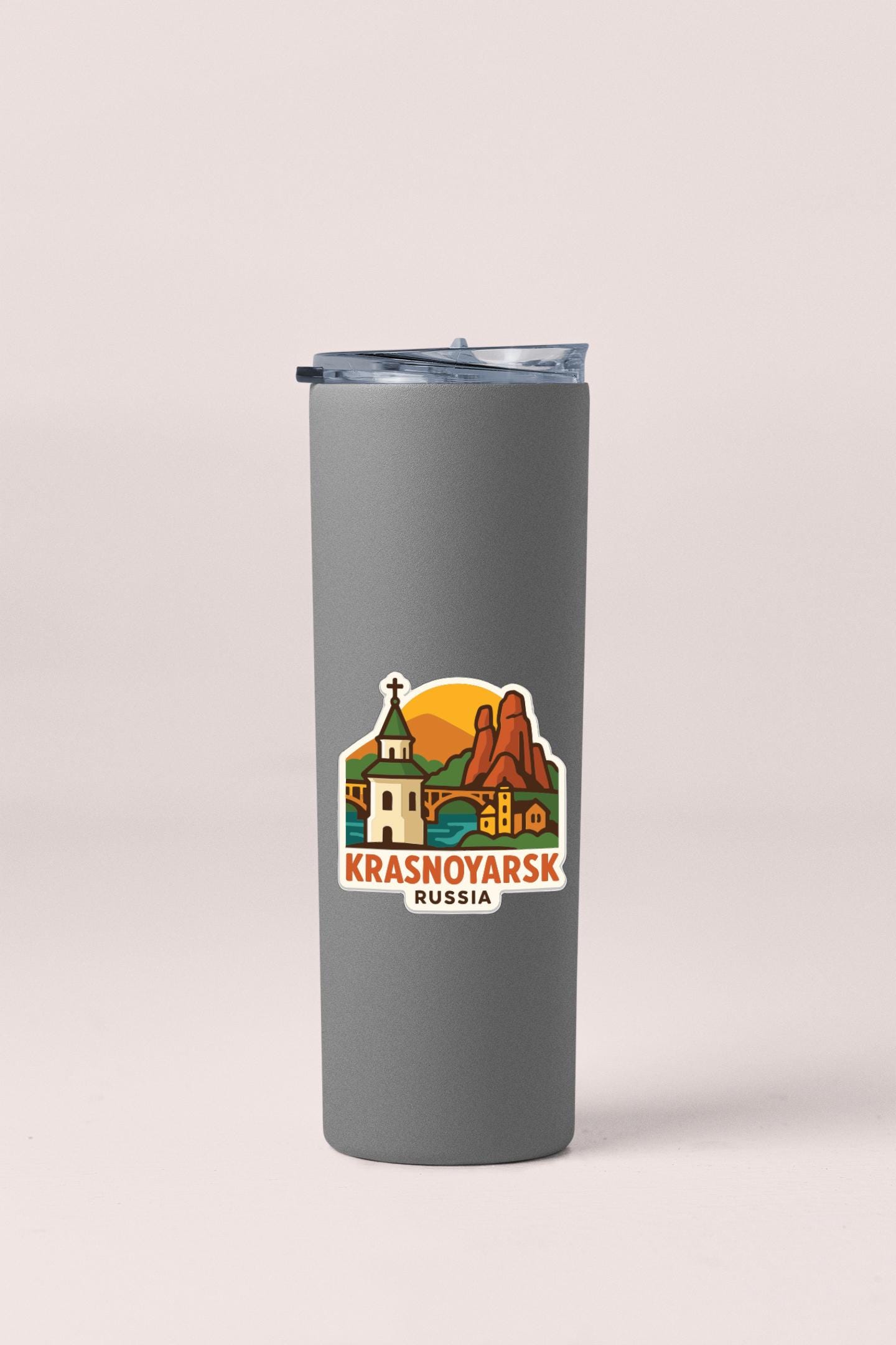 A gray tumbler with a sticker depicting a scenic landscape and the text "Krasnoyarsk Russia" printed on it.