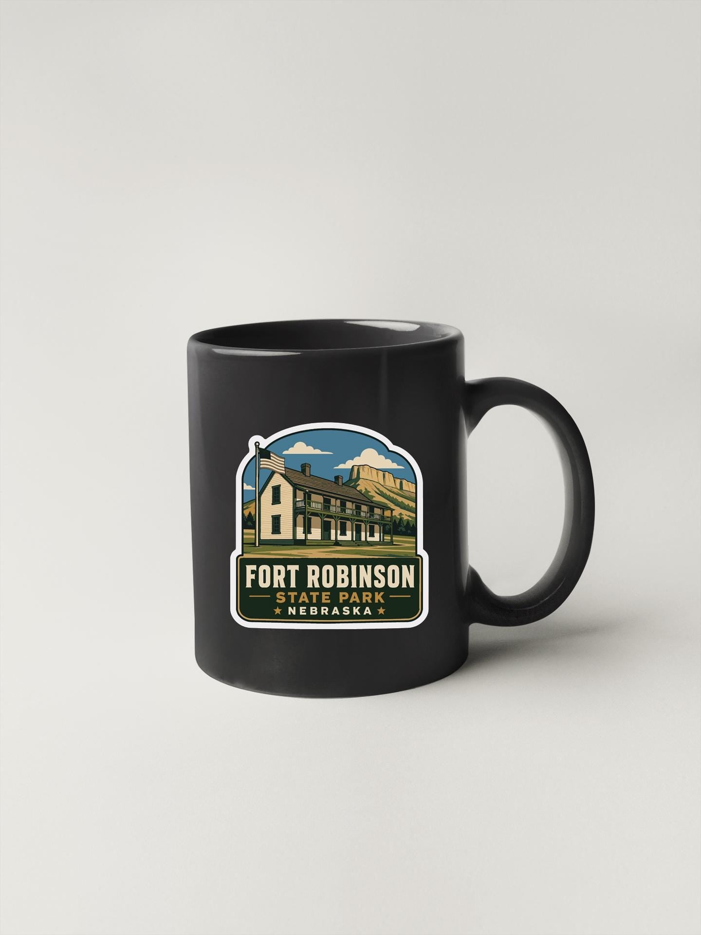 A black coffee mug with a graphic design featuring a house and the text "FORT ROBINSON STATE PARK NEBRASKA".
