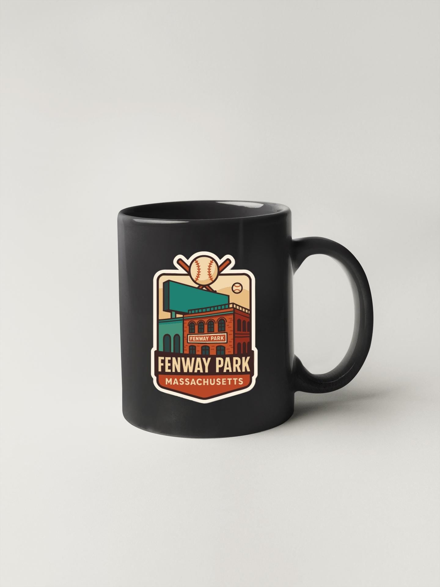 A black coffee mug with a colorful graphic design depicting Fenway Park, a baseball stadium in Boston, Massachusetts.