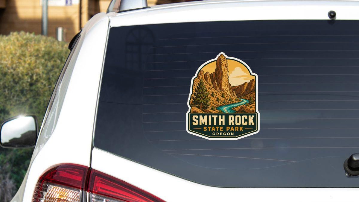 A sticker on the rear window of a white vehicle, depicting a scenic landscape with a mountain and a river.