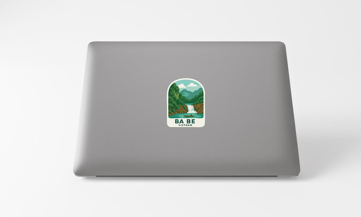 a sticker with a mountain landscape and a waterfall on the back of a laptop.