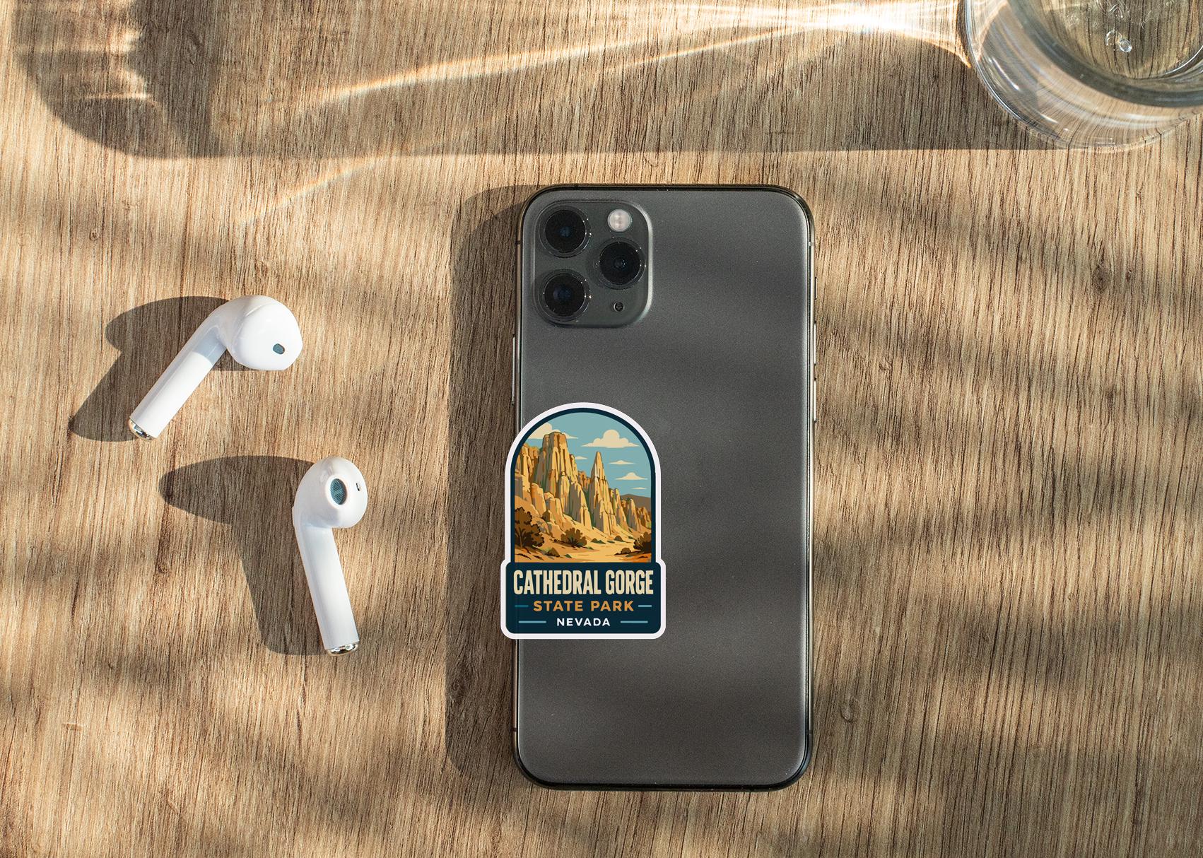 a smartphone with a sticker of Cathedral Gorge, a famous landmark in Nevada, placed on the back of the phone. The phone is also accompanied by a pair of white earbuds and a glass of water, all resting on a wooden surface.