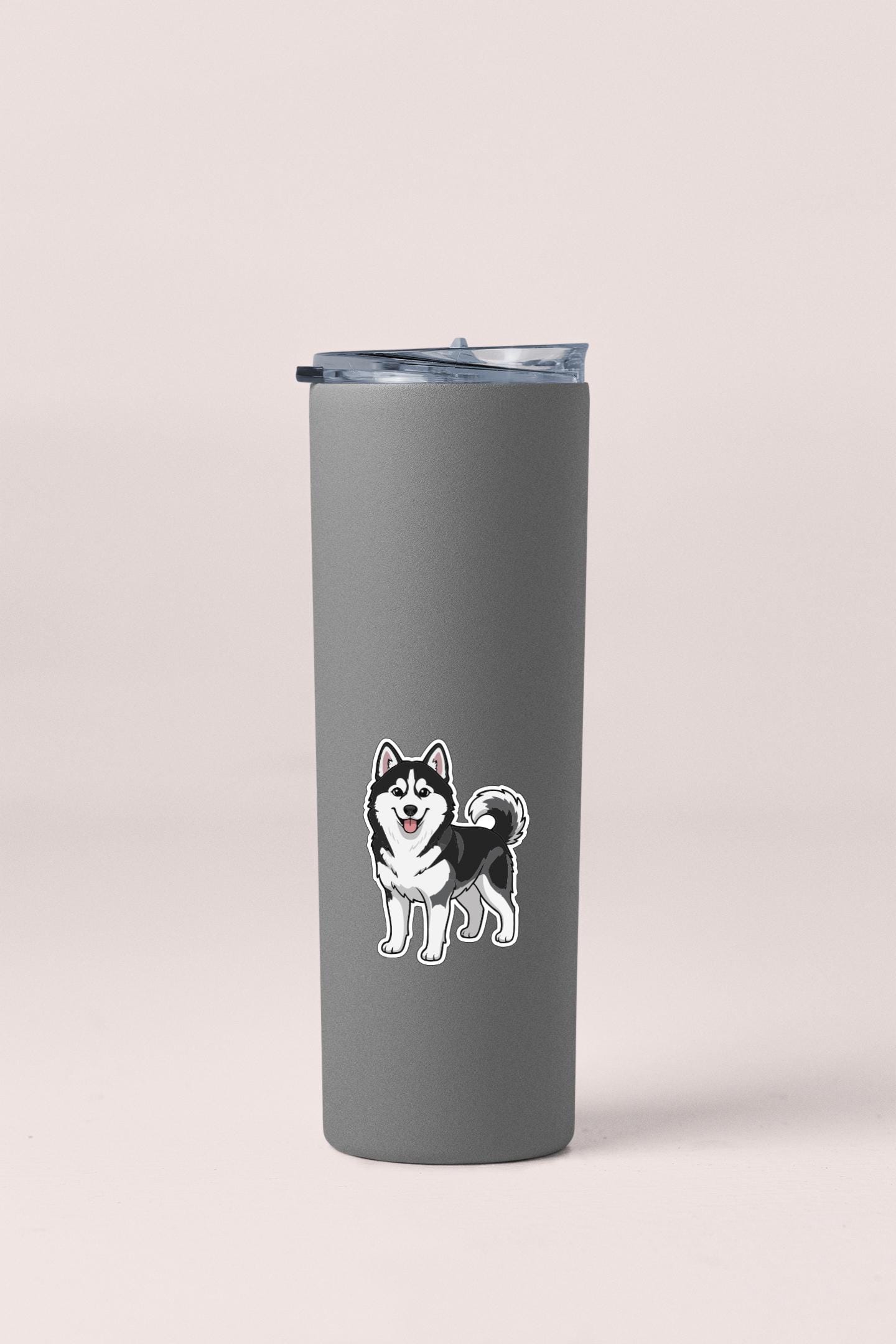 A gray insulated tumbler with a sticker of a husky dog on it.
