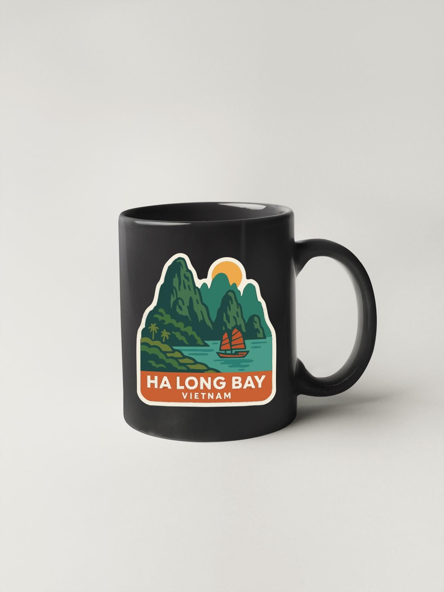 A black coffee mug with a colorful illustration depicting a scenic landscape with mountains, a river, and a sailboat.