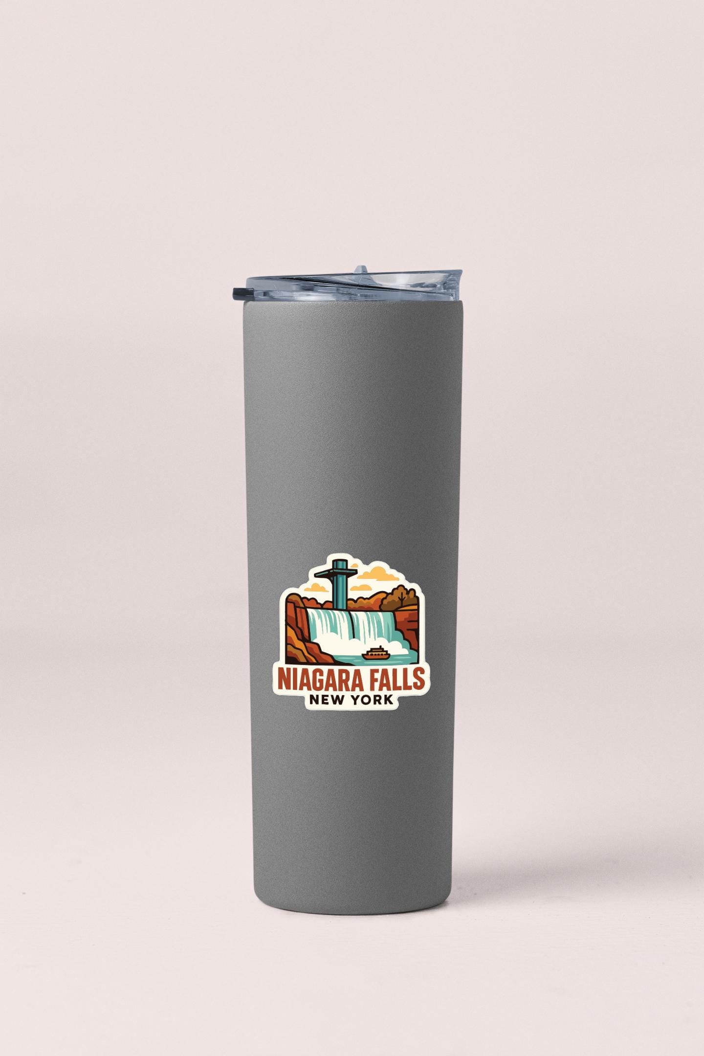 A gray insulated tumbler with a printed logo depicting Niagara Falls, New York.