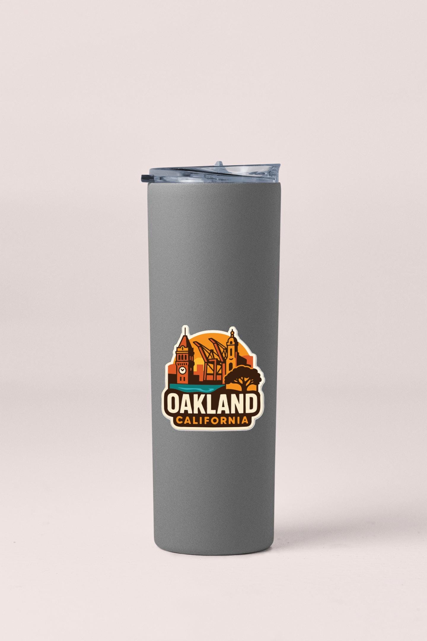 A gray insulated tumbler with a sticker that says "Oakland California".