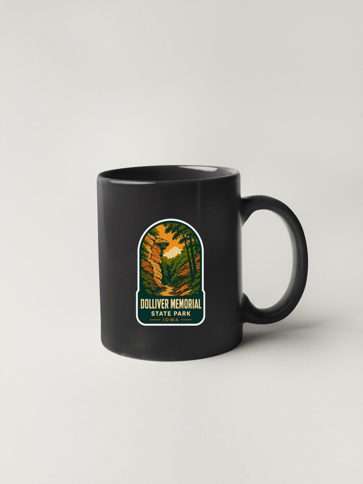 A black coffee mug with a sticker depicting a scenic landscape, labeled "Dolliver Memorial State Park".