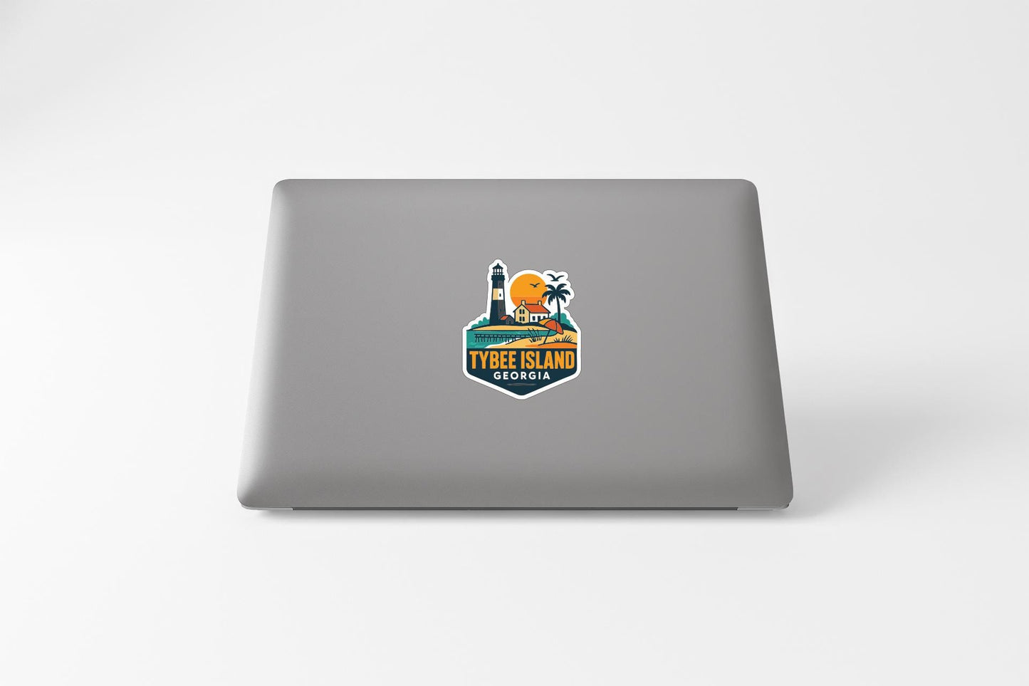 A sticker on the back of a laptop, depicting a tropical island scene with a lighthouse and palm trees.