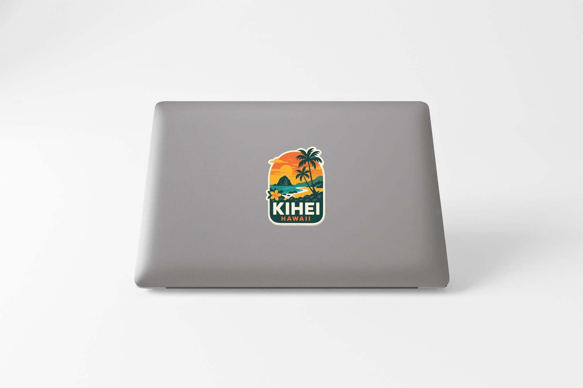 A sticker with a tropical beach scene and palm trees, along with the text "KIEI HAWAII" printed on a laptop.