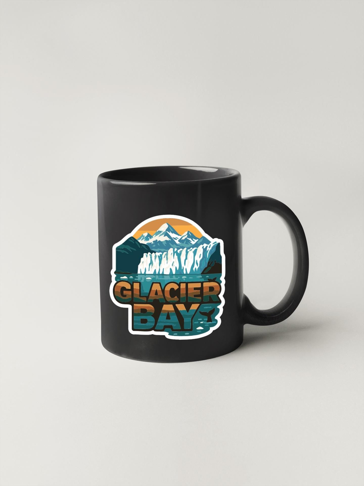 A black coffee mug with a graphic design featuring a mountain landscape and the text "GLACIER BAY".