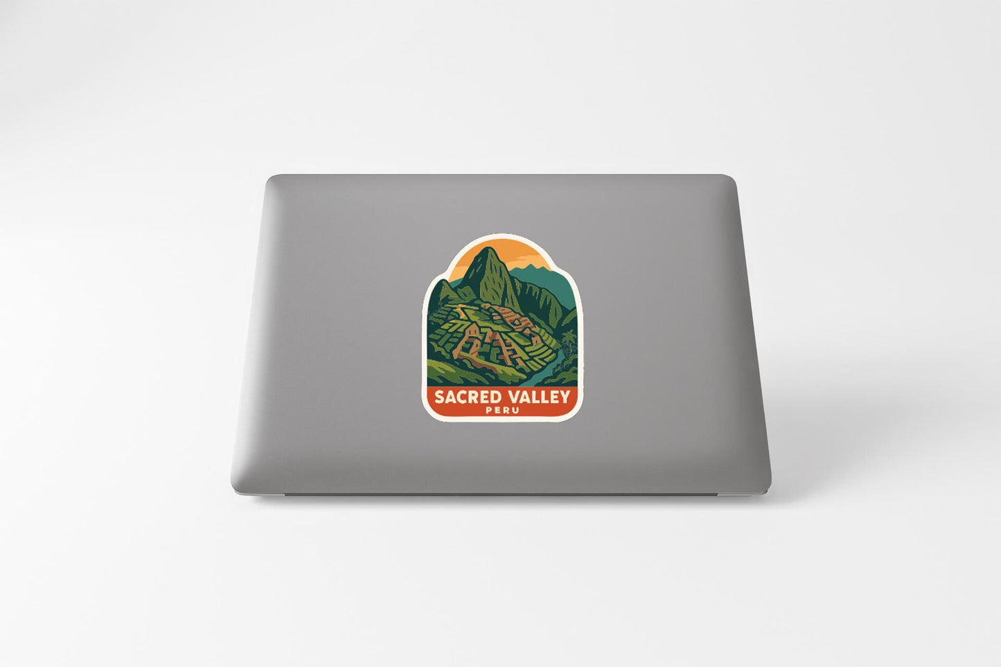 A sticker on the back of a laptop, depicting a scenic landscape with mountains and a valley.