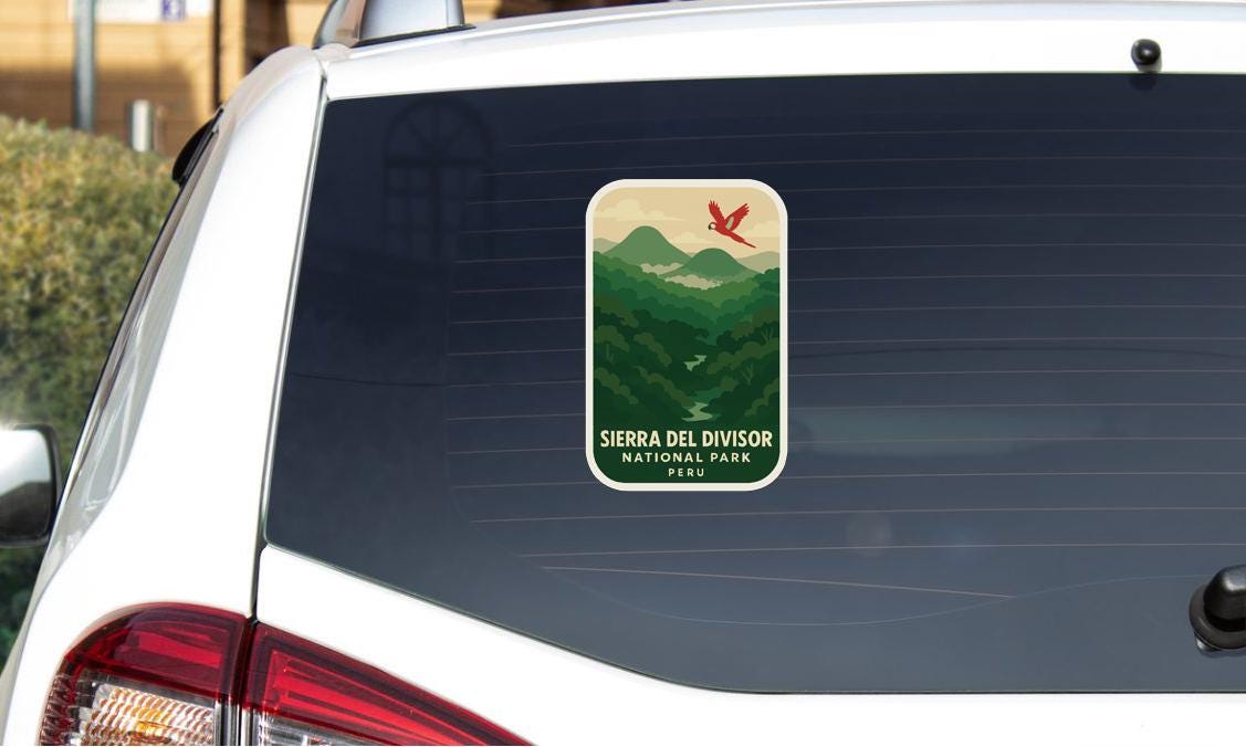 a sticker on the rear window of a car, depicting a scenic mountain landscape with a red bird in flight.