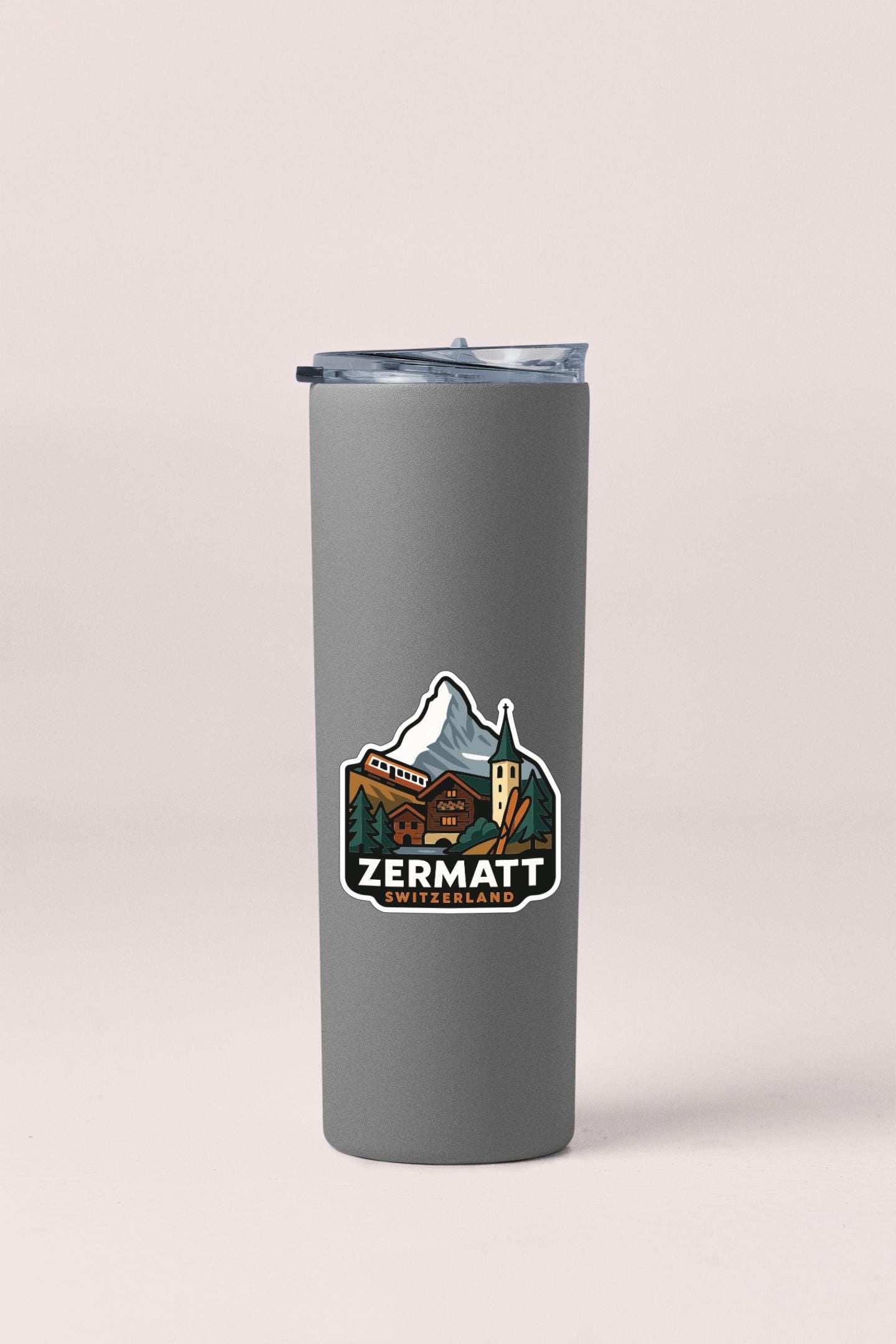 A gray insulated tumbler with a mountain and chalet-style illustration on it, along with the text "ZERMATT SWITZERLAND".
