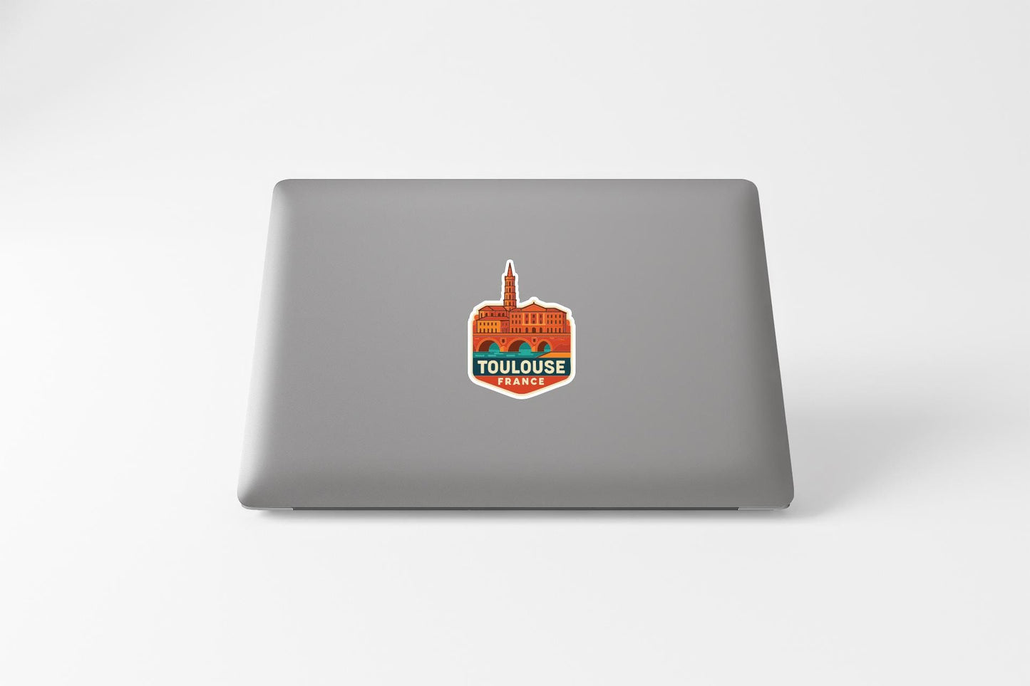 A sticker with an illustration of a building and the text "TOULOUSE PARIS" on a laptop.