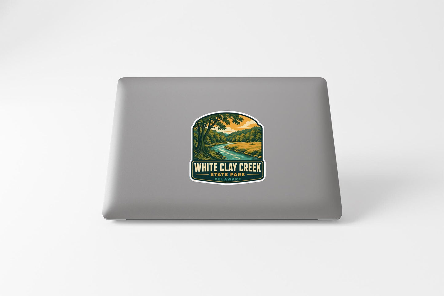 a sticker on a laptop that displays a scenic landscape with a river and trees.