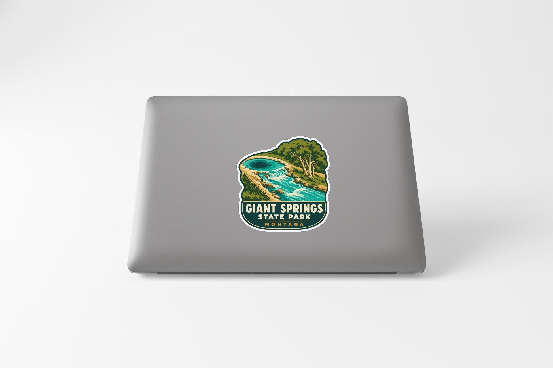 a sticker on a laptop that displays a scenic landscape with a river and trees.