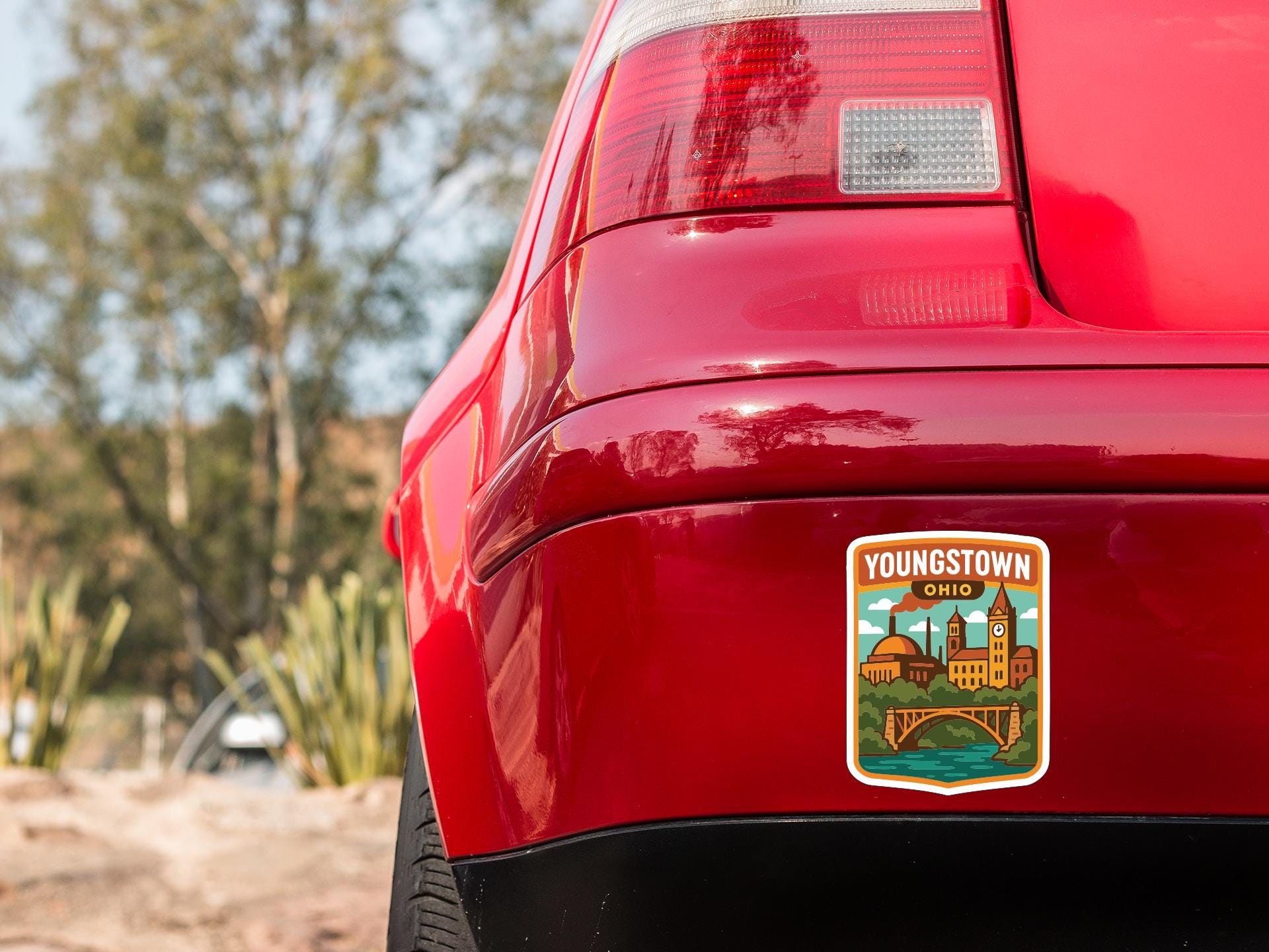 the rear end of a red car with a sticker on the trunk that says "YOUNGSTOWN, OHIO".