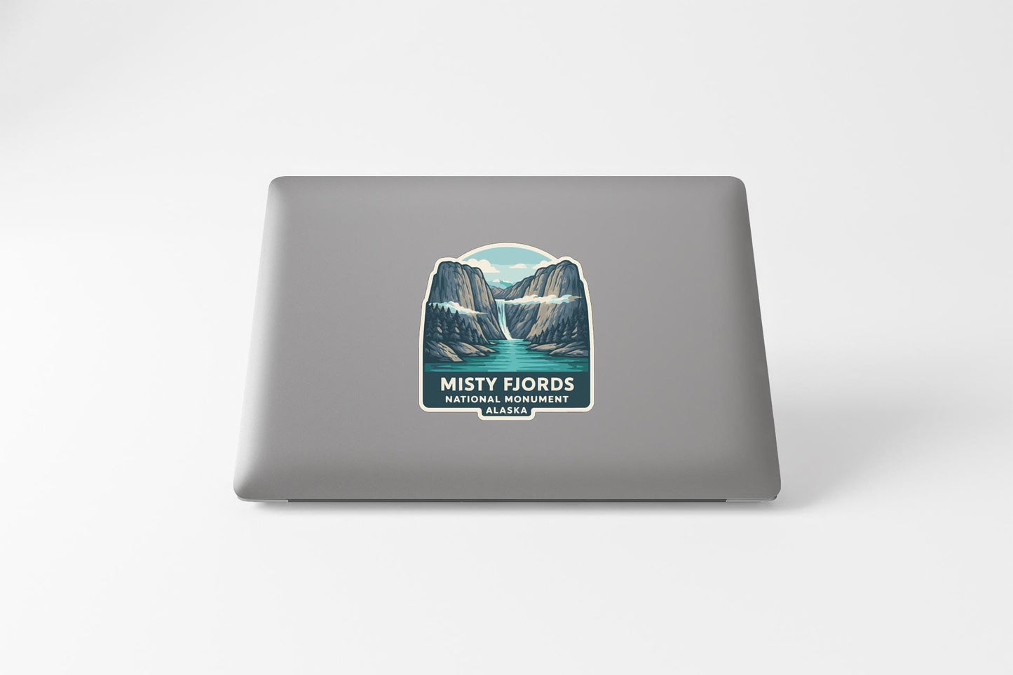 a sticker on the back of a laptop that depicts a scenic mountain landscape with a lake.